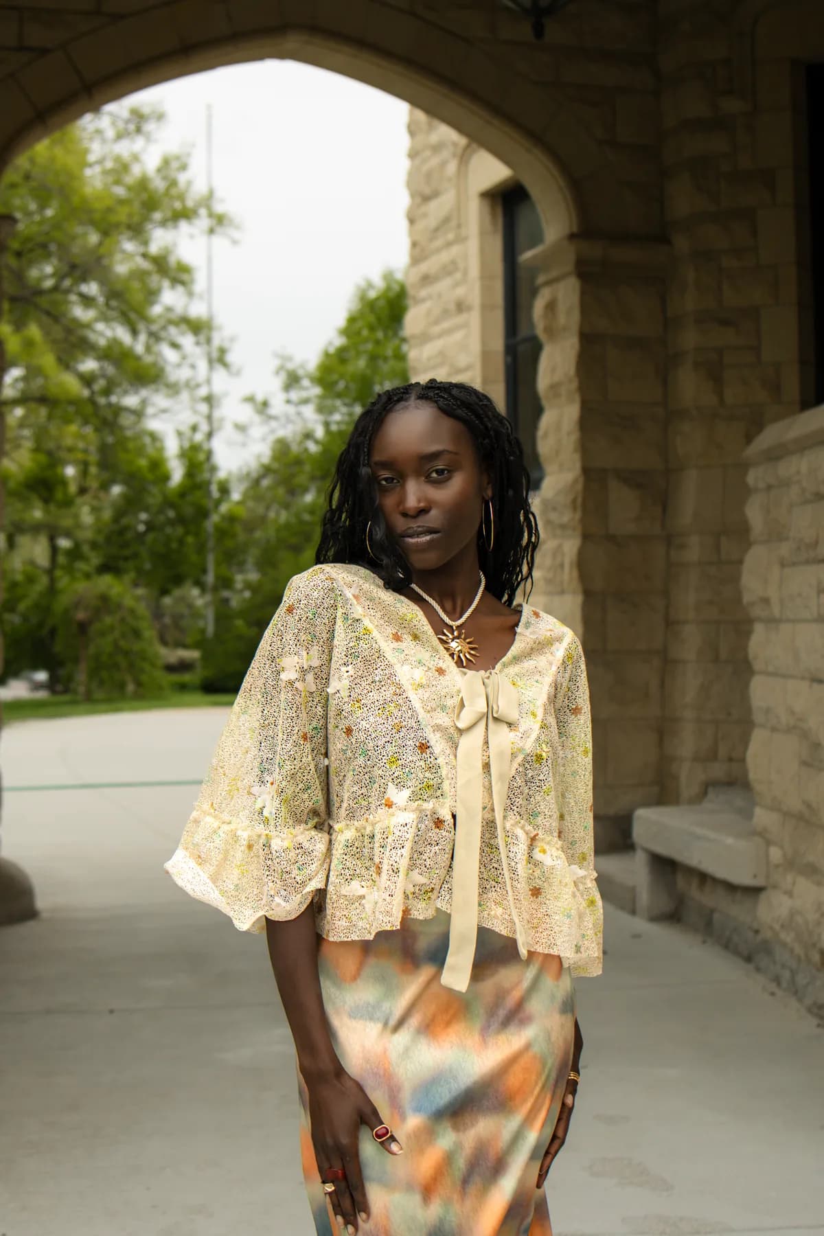 a woman under a stone archway in a sheer floral popover and a watercolour midi skirt